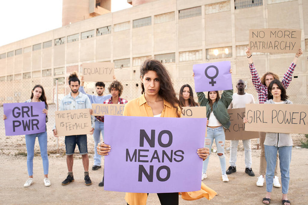 Gruppo di persone che tengono cartello con parola vicino femminista. - Foto, immagini