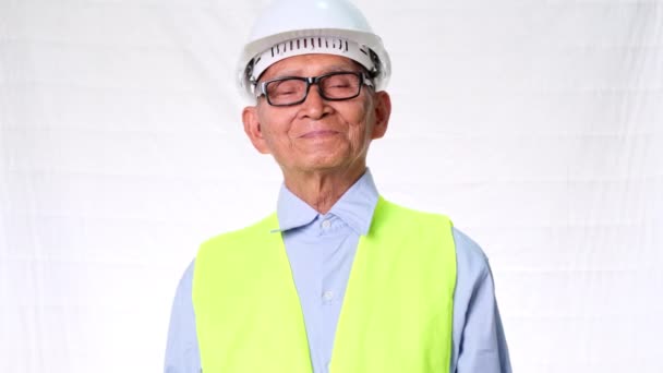 Fiducioso architetto senior engineering indossa giubbotto e casco su sfondo bianco in studio. - Filmati, video