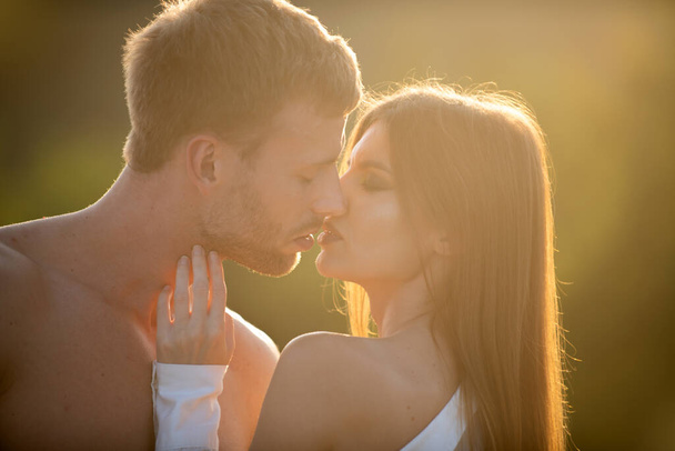 Sensual kiss. Man kissed tender woman. Portrait of lovely couple in love. Young sensual girlfriend glad to passionate kiss from her boyfriend. Handsome young man embraces woman and kisses at sunset. - Foto, afbeelding