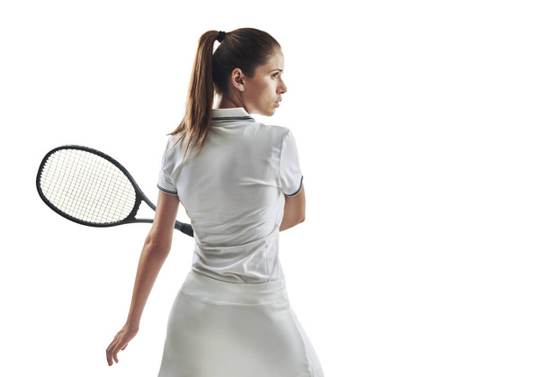 No pueden detener lo que no pueden atrapar. Captura de estudio de una jugadora de tenis sosteniendo una raqueta sobre un fondo blanco. - Foto, imagen