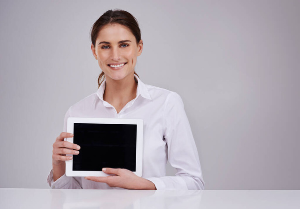 Sua presença online é importante. Retrato de estúdio de uma jovem atraente segurando um tablet digital em branco. - Foto, Imagem