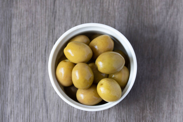 Мариновані зелені оливки в мисці
 - Фото, зображення