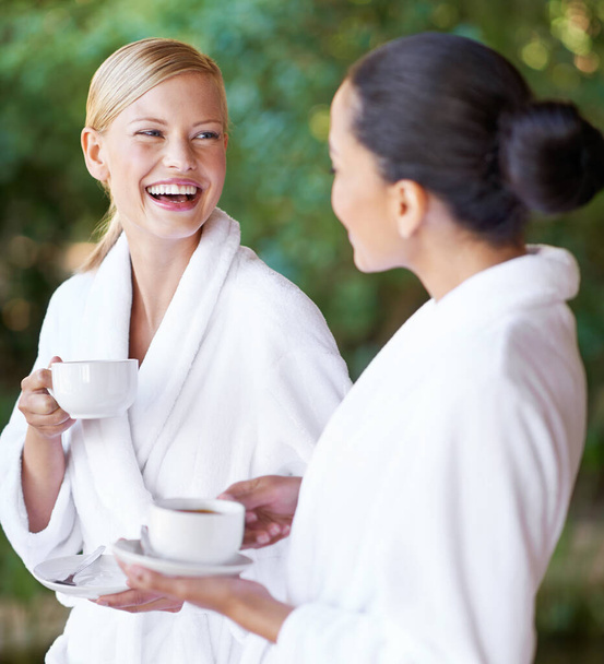 Disfrutando de una sesión de mimos con un buen amigo. Dos mujeres jóvenes tomando café en sus albornoces en el spa. - Foto, Imagen