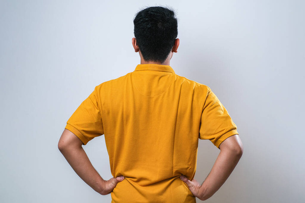 joven asiático hombre usando casual camisa sobre blanco fondo de pie hacia atrás mirando lejos con brazos en cuerpo - Foto, Imagen