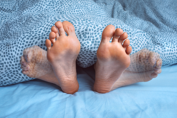 Nainen, jolla on jalkakramppeja, jalkakramppeja tai lihaskouristuksia nukkuessaan. Jalat kipua tai jalkoja särkee yöllä. Levottomat jalat oireyhtymä - Valokuva, kuva