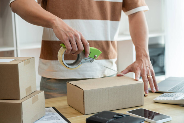 Online-Shopping-Konzept: Verkäufer versiegelt das Paket seiner Ware auf dem Schreibtisch. - Foto, Bild