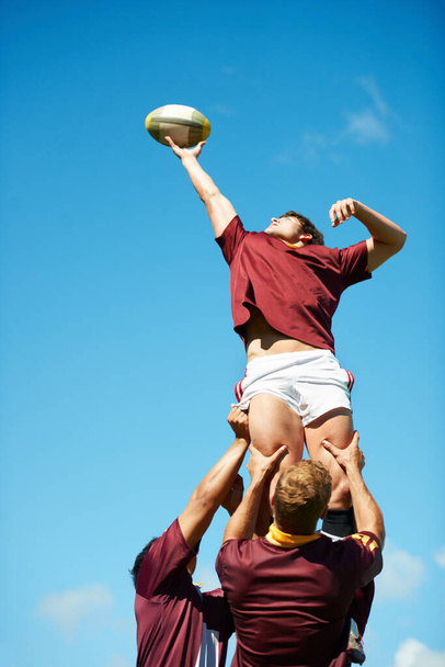 Catturare un momento epico. Colpo di un giovane giocatore di rugby che prende la palla durante una rissa. - Foto, immagini