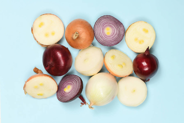 Three onion bulbs of different colors (red, yellow and white) isolated on blue background. High resolution photo. Full depth of field. - Photo, Image