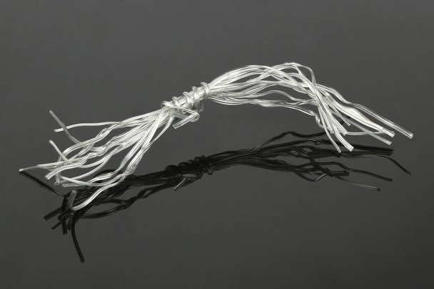 Bílá plastová drátěná kravata používaná pro různé věci na černém akrylovém pozadí. Fotka ve vysokém rozlišení. Plná hloubka pole. - Fotografie, Obrázek