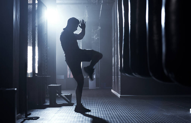 Az igazi harcosok ösztönösen vadak. Egy sportos fiatal férfi kickboxolt egy edzőteremben.. - Fotó, kép