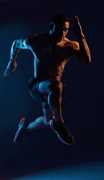 The hardest workout builds the hardest body. Studio shot of a handsome young man working out against a dark background. - Foto, Imagem