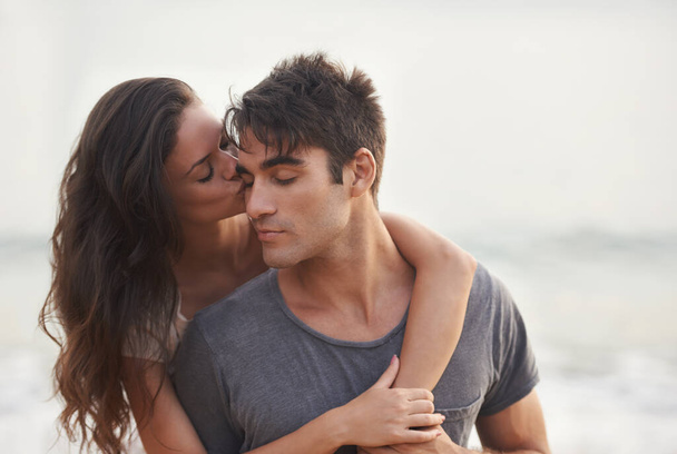 Lucky in love. Cropped shot of an affectionate young couple at the beach. - 写真・画像