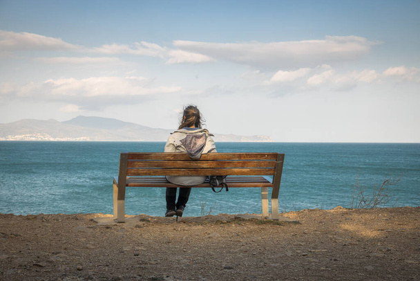 Egy nő ül egy padon, nyugodt tekintettel a tengerre a Costa Brava-n - Fotó, kép