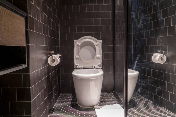 Черная ванная комната с белым туалетом и белым полотенцем
 - Фото, изображение