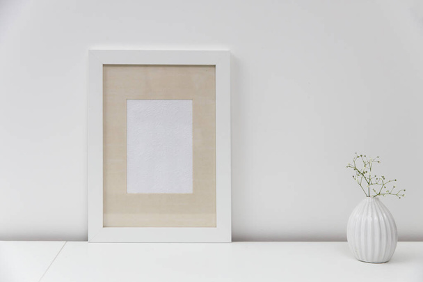Blank canvas frame mockup. Artwork in interior design. View of modern scandinavian style interior with canvas for painting or poster on wall. Living room, commode with vases. Minimalism concept - 写真・画像