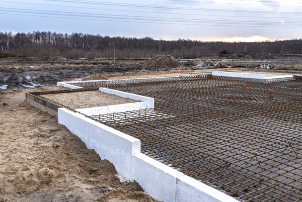 The foundation slab is made of reinforcement rods, bound with tie wire, visible sewage pipes. - Photo, Image