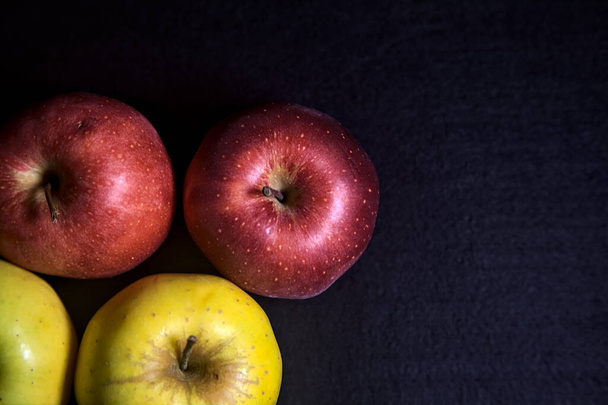 Κόκκινα και κίτρινα μήλα σε μαύρο φόντο - Φωτογραφία, εικόνα