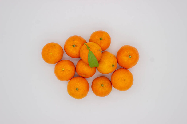 Wenige reife Mandarinen mit grünen Blättern auf weißem Hintergrund - Foto, Bild