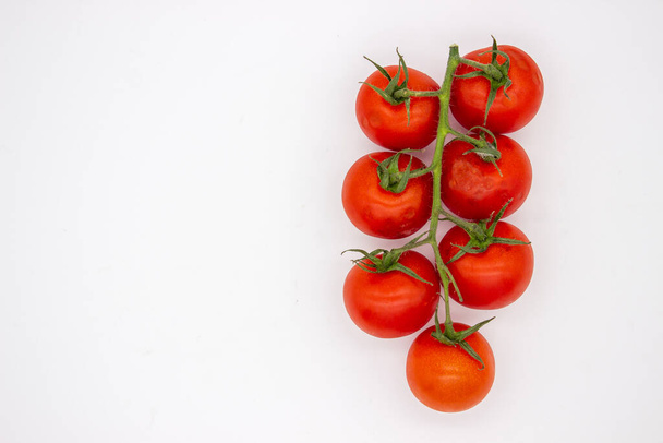 Cherry tomatoes on branch stand on white background. Isolated image - Valokuva, kuva