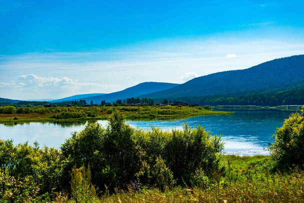 Landscape of the river bank in Siberia. bright juicy colors hilly riverbank and blue clouds. - Zdjęcie, obraz