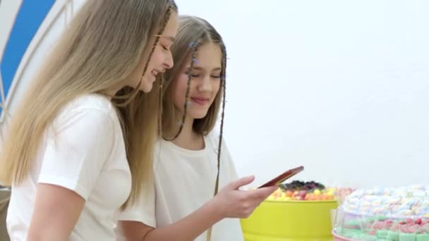Deux copines dans le magasin prennent des photos de bonbons avec un smartphone,  - Séquence, vidéo