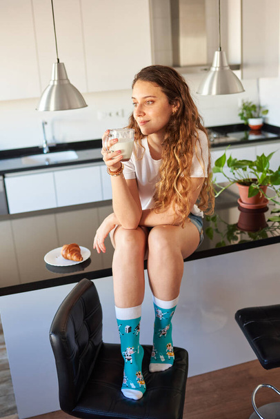 Young woman drinking milk in the kitchen - Photo, Image