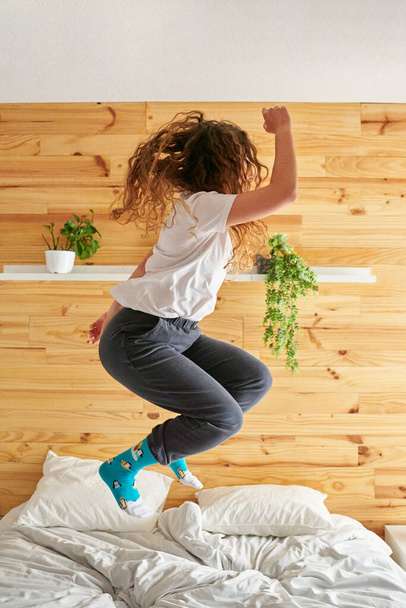 Irriconoscibile giovane donna che salta energicamente sul letto - Foto, immagini
