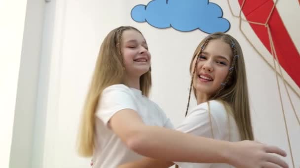 Twee kleine zusjes knuffelen oprecht, ze dragen witte T-shirts. - Video