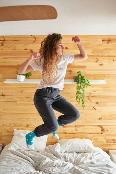 Young woman jumping energetically on bed - Foto, immagini