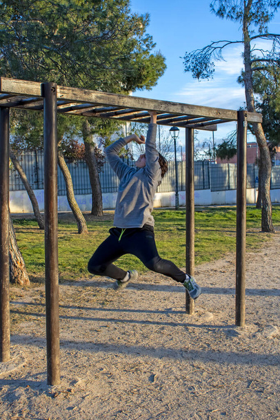 Teenage doing exercise in a park with parallel bars - Photo, Image