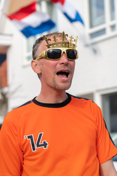 Hollantilainen juhlii kuninkaiden päivää tiellä Hollannissa oranssiin pukeutuneissa katujuhlissa. Koningsdag on perinteinen festivaali Alankomaiden kuninkaallisen perheen kunniaksi. Alankomaiden lippu ja bunting koristelu taloa. - Valokuva, kuva