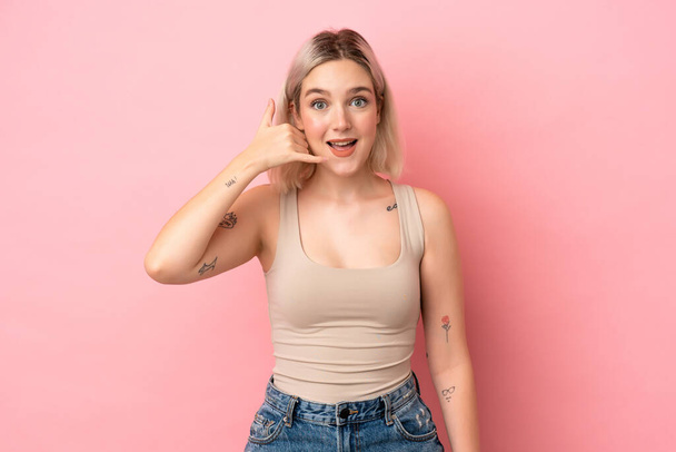Young caucasian woman isolated on pink background making phone gesture. Call me back sign - Photo, Image