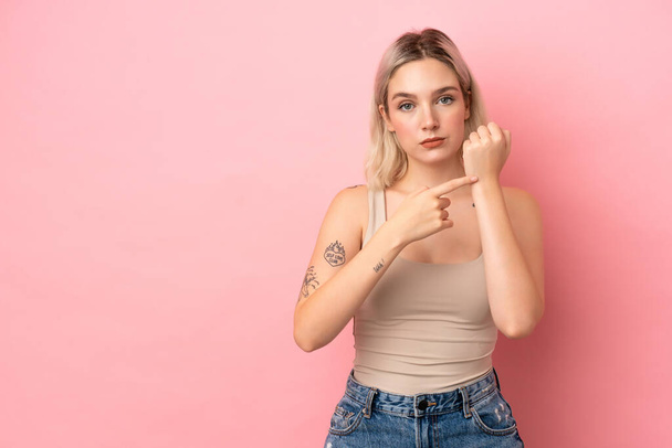 Young caucasian woman isolated on pink background making the gesture of being late - Photo, Image
