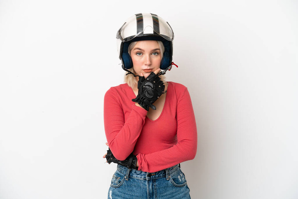 Jeune femme caucasienne avec un casque de moto isolé sur fond blanc pensant - Photo, image