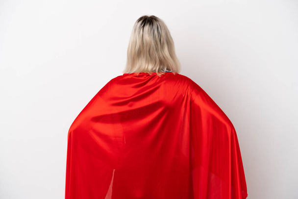 Mujer joven caucásica aislada sobre fondo blanco en traje de superhéroe en la posición trasera - Foto, Imagen