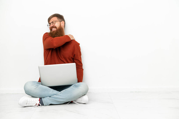Jonge roodachtige blanke man met laptop geïsoleerd op witte achtergrond die lijdt aan pijn in de schouder voor het hebben van een inspanning - Foto, afbeelding