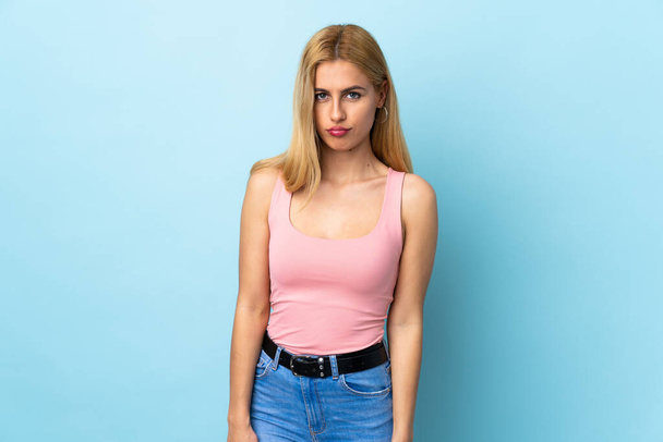 Young Uruguayan blonde woman over isolated blue background with sad expression - Fotó, kép