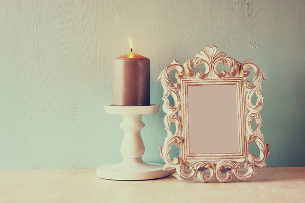 Low key image of vintage antique classical frame and Burning candle on wooden table. filtered image - 写真・画像