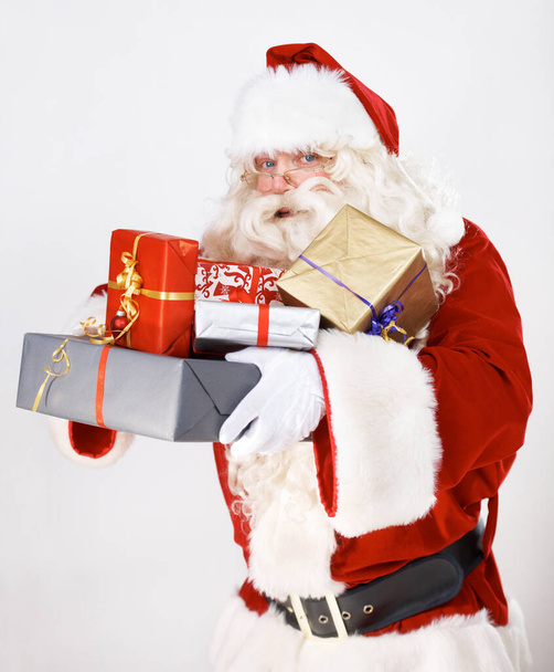 Te traigo magia navideña. Santa Claus sosteniendo una pila de regalos de Navidad envueltos - retrato. - Foto, Imagen