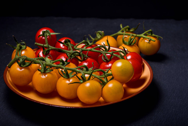 Mini-rote und gelbe Tomaten vor dunklem Hintergrund. Lebensmittel-Fotografie - Foto, Bild