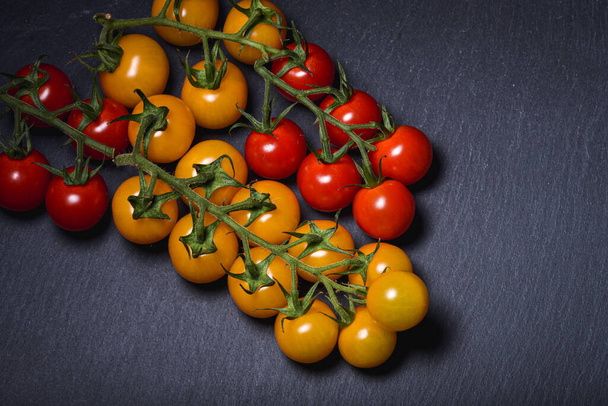 Мини-красные и желтые помидоры на темном фоне сценариев. Фотография еды - Фото, изображение