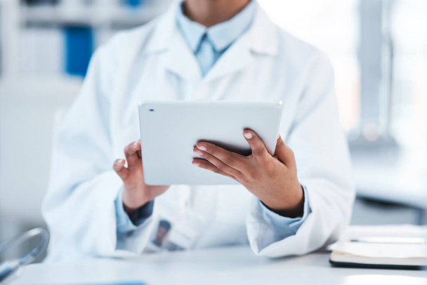 Technology is a vital tool in this lab. Closeup shot of an unrecognisable scientist using a digital tablet in a lab. - Photo, Image