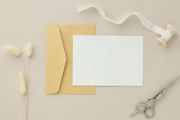 Tyhjä tervehdys kortti kutsu Mockup 5x7 Brown kirjekuori kuivattuja kukkia beige tausta, tasainen lay, mockup - Valokuva, kuva