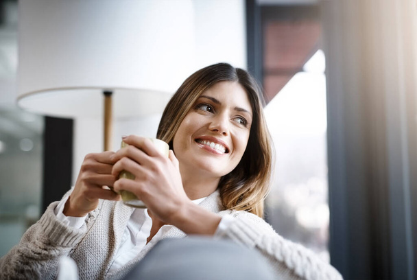 Un sorbo de café es todo lo que se necesita.... Foto recortada de una mujer joven disfrutando de una taza de café mientras se relaja en casa. - Foto, Imagen