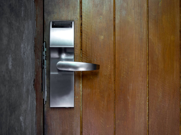 Çimento duvarında eski kahverengi ahşap kapı kolunda kapı zili olan akıllı, irtibatsız anahtar kartı sistemi. Otelin giriş kapısının elektrik kontrolü. - Fotoğraf, Görsel