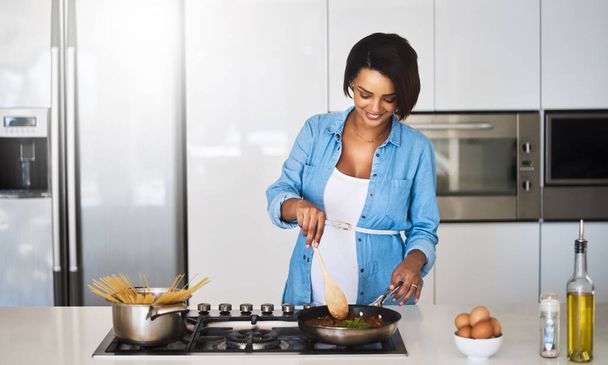 Ses bébés vont adorer les pâtes. Prise de vue d'une jeune femme enceinte préparant un repas sur le poêle à la maison. - Photo, image