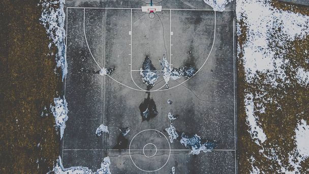 雪がバスケットボールコートを公開溶融し始めている - 写真・画像