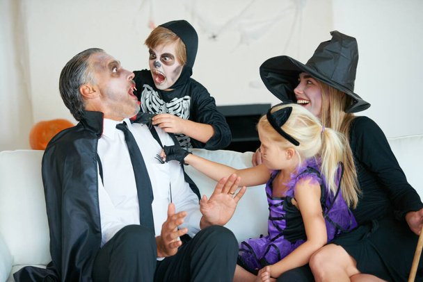 Beste tijd van het jaar voor angst. Een leuke familie verkleed voor Halloween allemaal proberen om elkaar bang te maken. - Foto, afbeelding