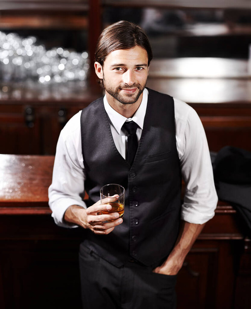 Просто расслабляюсь. Портрет хорошо одетого молодого человека, сидящего в баре с напитком. - Фото, изображение