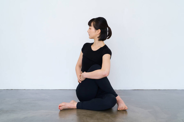 vrouw zitten en doen yoga binnen met zwarte slijtage - Foto, afbeelding